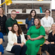 The AMBITIOUS team sat and standing around a sofa.